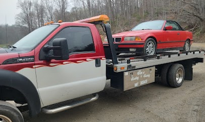 Flatbed tow truck carrying a red car